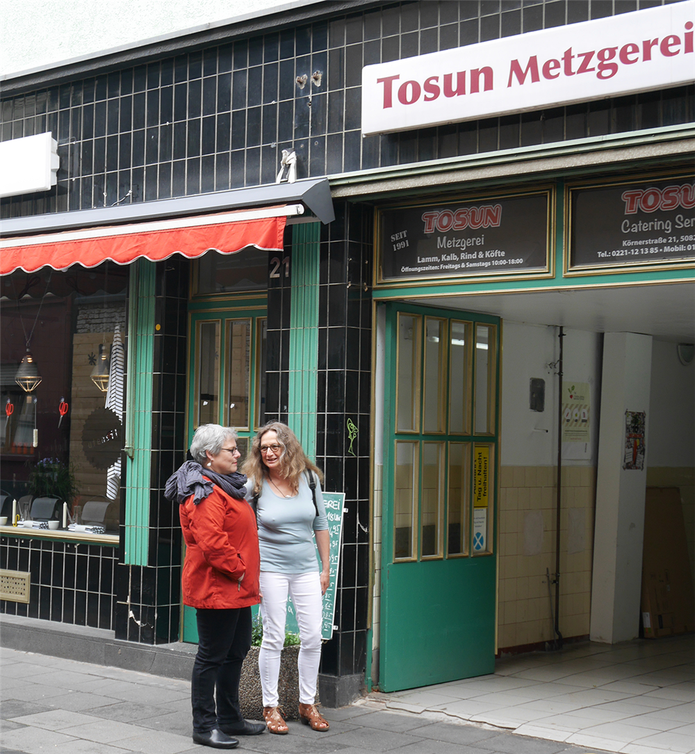 Michaela Pfaff und Anne Kuhlmann stehen vor dem geöffneten Eingang der Tosun Metzgerei in Köln-Ehrenfeld (Julia Hitschfeld/Caritas)