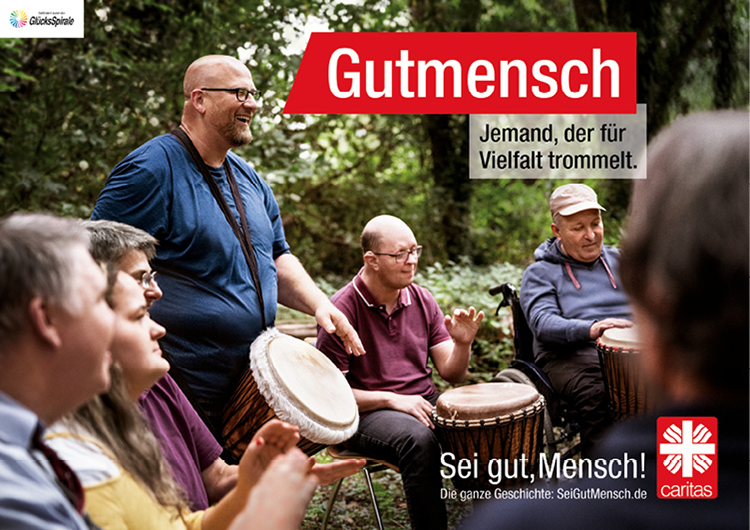 Motiv: Drei Männer mit Trommeln sitzen mit einigen anderen Personen in einem Wald (© Deutscher Caritasverband e. V./Sebastian Pfütze)