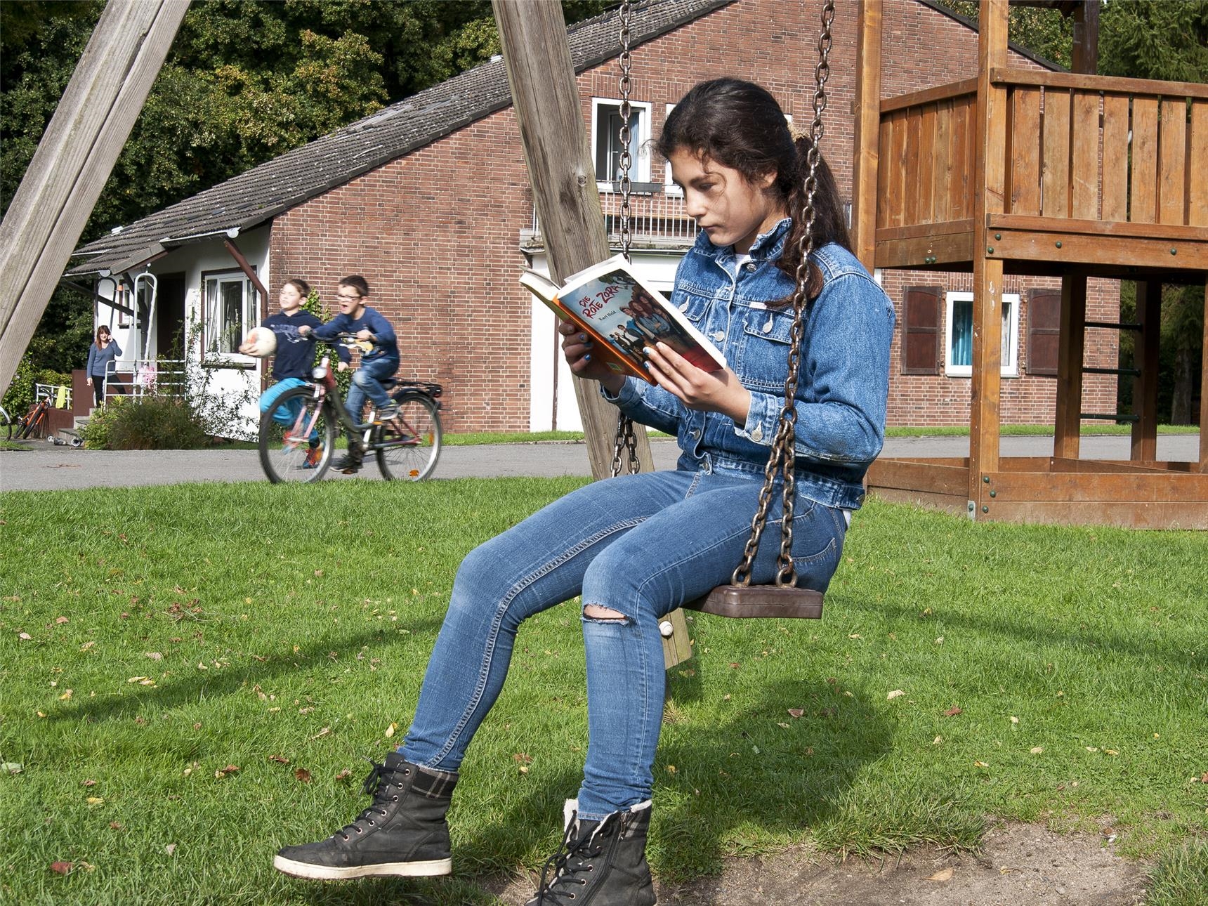 ein Mädchen sitzt auf der Schaukel und liest (Petra Lamers)
