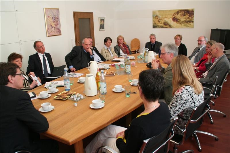 Das Foto zeigt eine Gruppe von Menschen, die um einen großen Tisch sitzt.