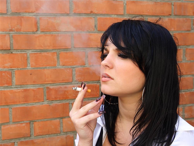 Eine schwarzhaarige Frau raucht eine Zigarette.