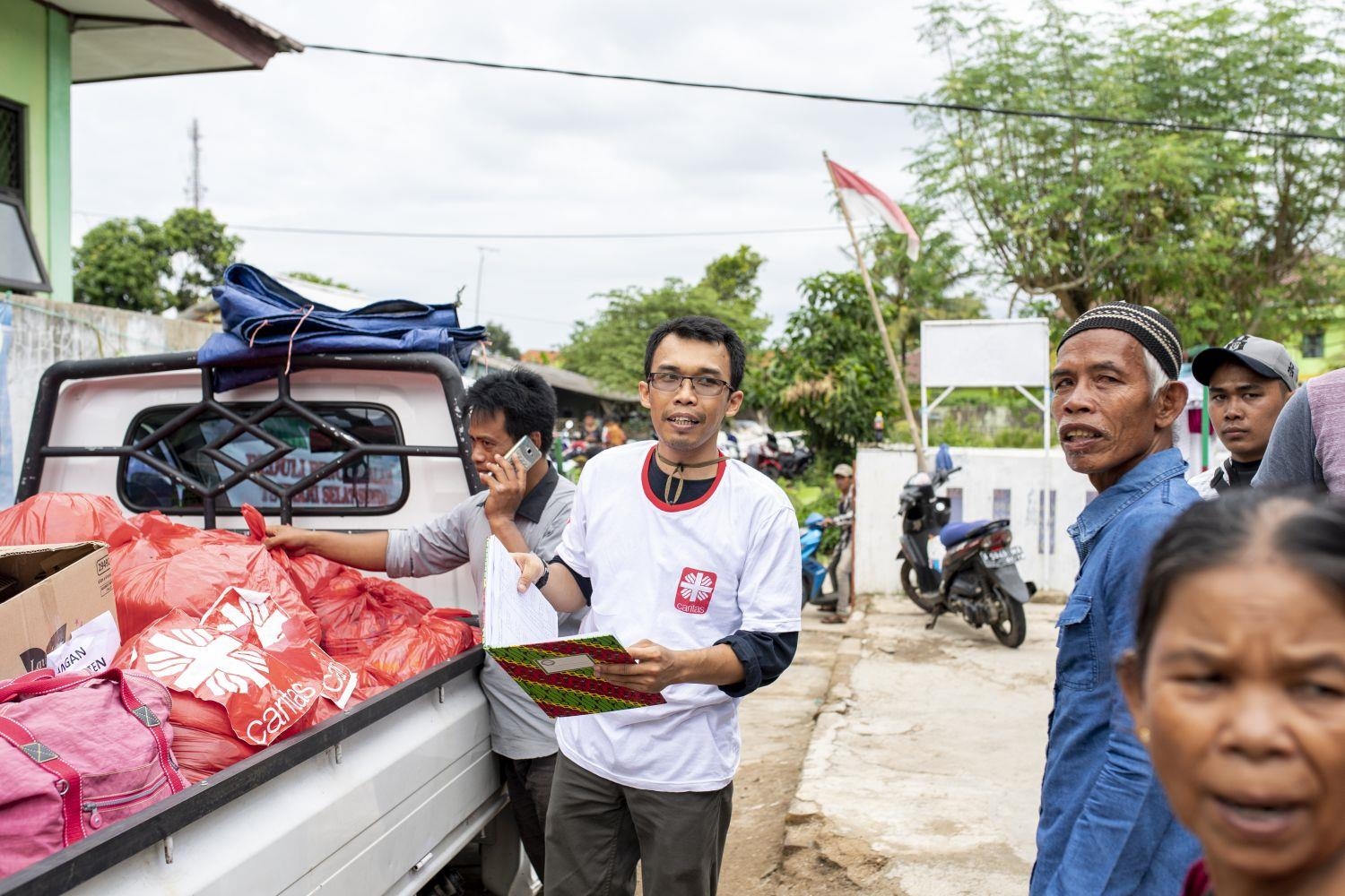 Katastrophenhelfer steht vor einem LKW mit Hilfsgütern in Indonesien  (Bente Stachowske / Caritas international)