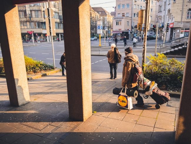 Obdachloser steht auf Gehweg vor dem Olgaplatz mit Plastiktüten. Darin bewahrt er seine wenigen Habseligkeiten auf.