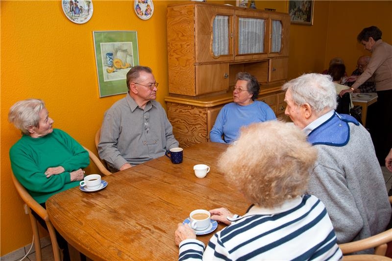 Fünf Menschen sitzen an einem Tisch, trinken Kaffee und unterhalten sich. (© Caritasverband Worms e.V.)