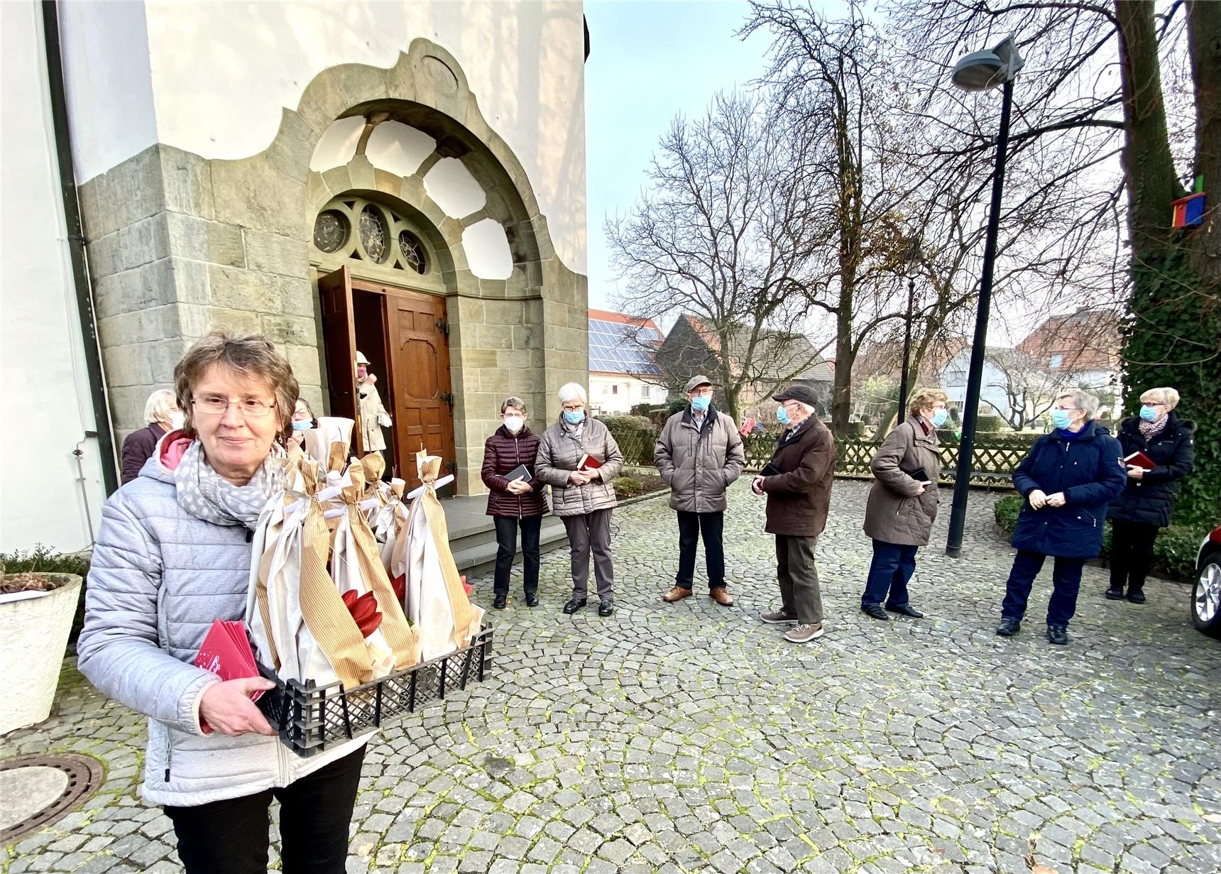 eine Frau mit einem Präsentkorb im Hintergrund Kirche und Gemeinde (CK Hovestadt-Nordwald-Schoneberg)