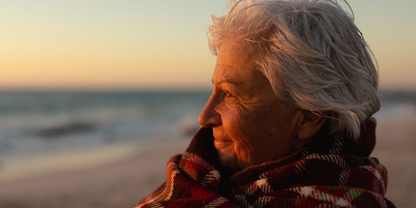 ältere Frau am Strand bei Sonnenuntergang