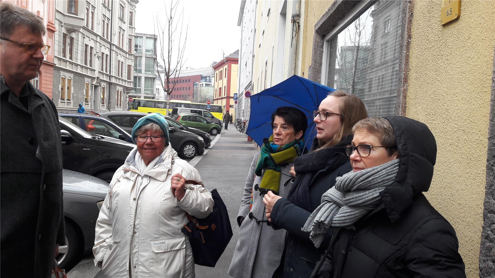 Vier Frauen stehen auf dem Gehweg, mit blauem Regenschirm (Peter Nagel)