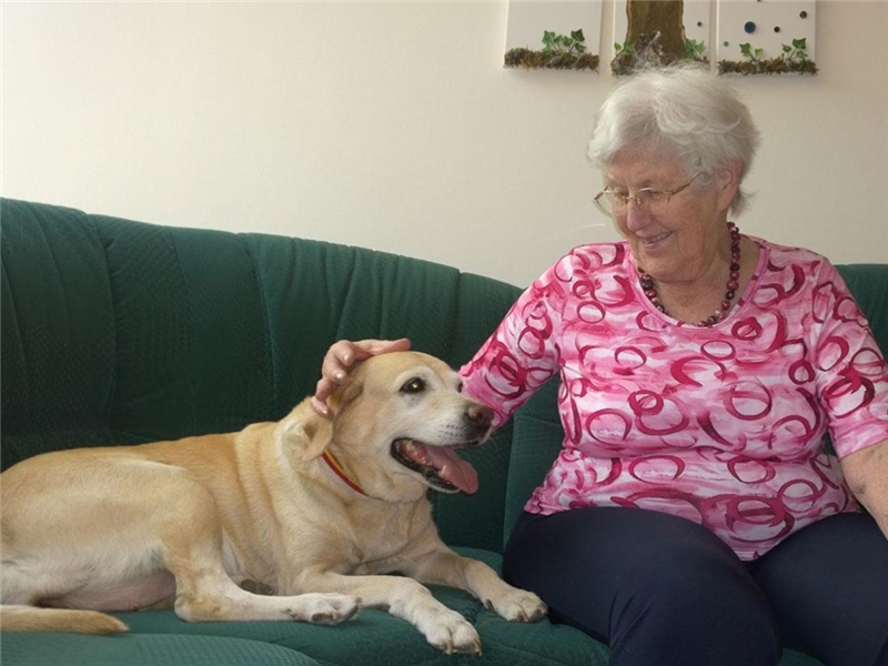 Hund und Seniorin auf Couch