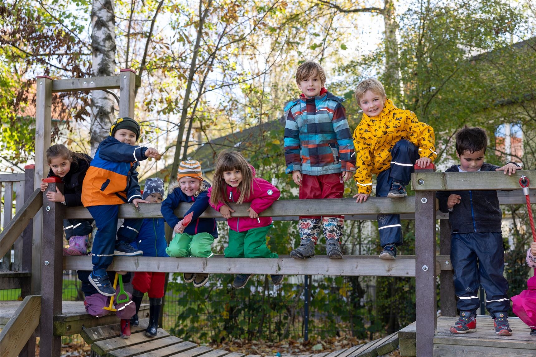 Kinder sitzen und stehen nebeneinander auf einem Klettergerüst 