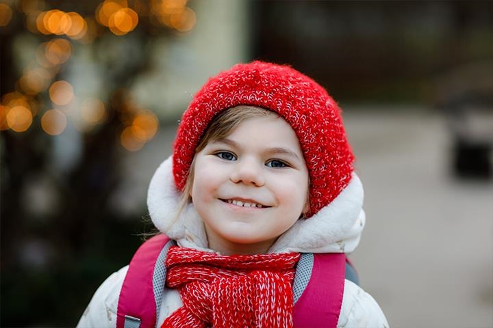 Ein Mädchen bekommt durch ihre Spende eine Wintermütze und Winterklamotten. 