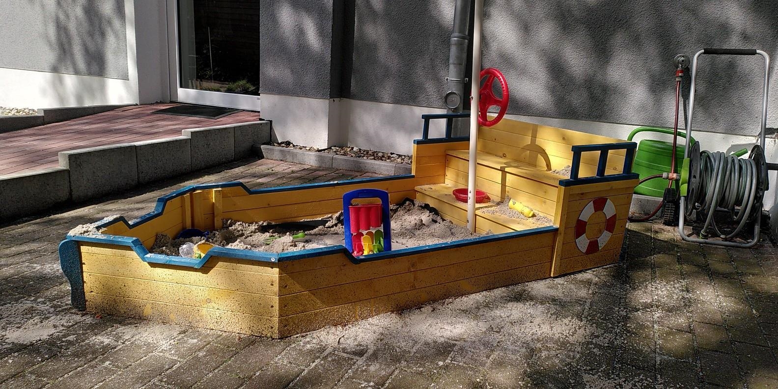 Ein kleines Holzboot dient als Sandkasten. 