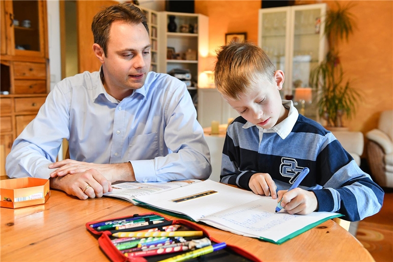 Das Foto zeigt einen Vater mit seinem Sohn bei Hausaufgaben.