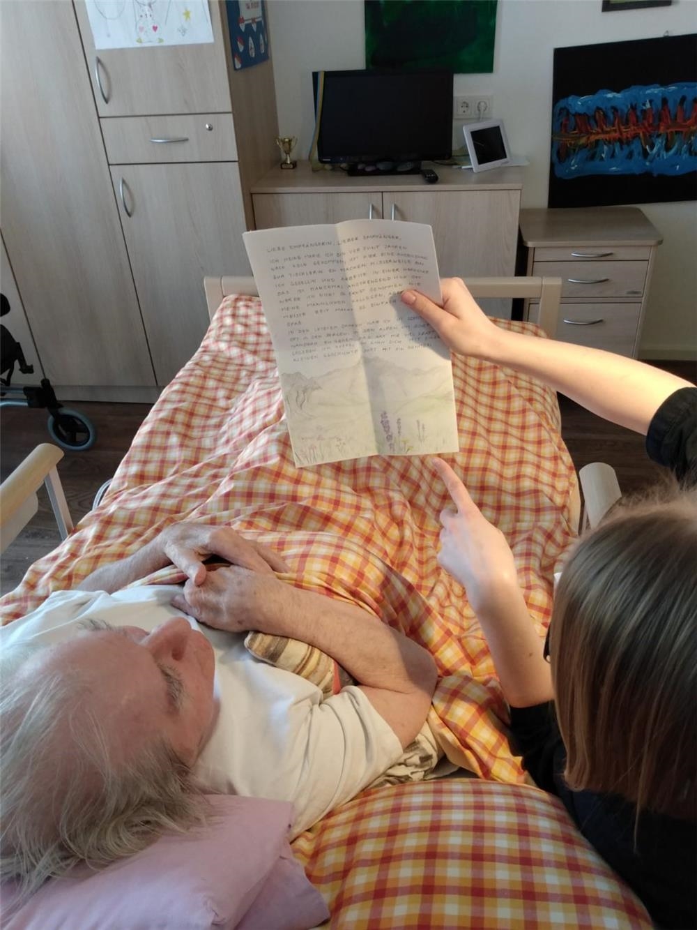 junge Frau mit Brief am Bett einer Seniorin (youngcaritas im Erzbistum Köln)