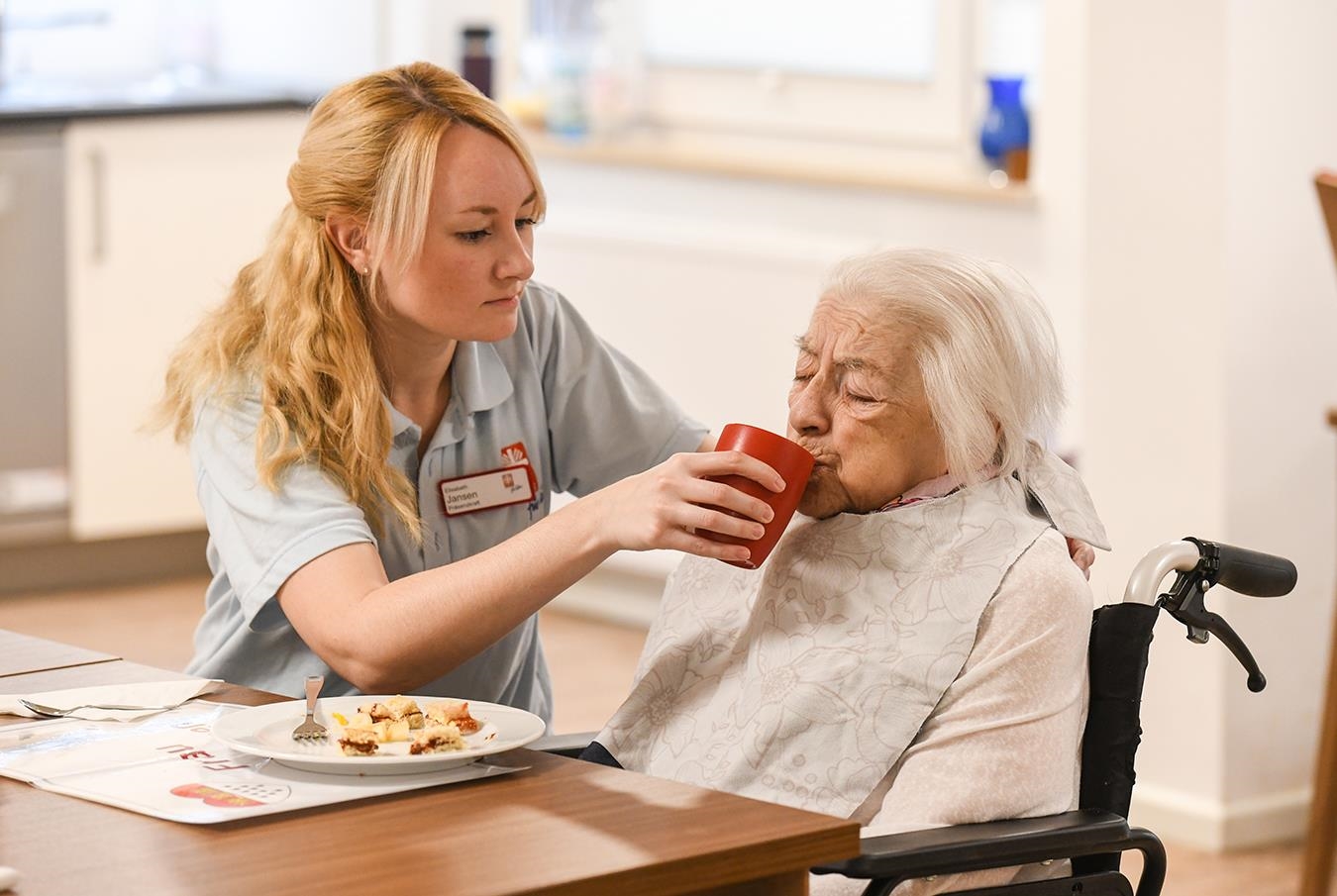 junge Pflegerin unterstützt Seniorin  beim Essen