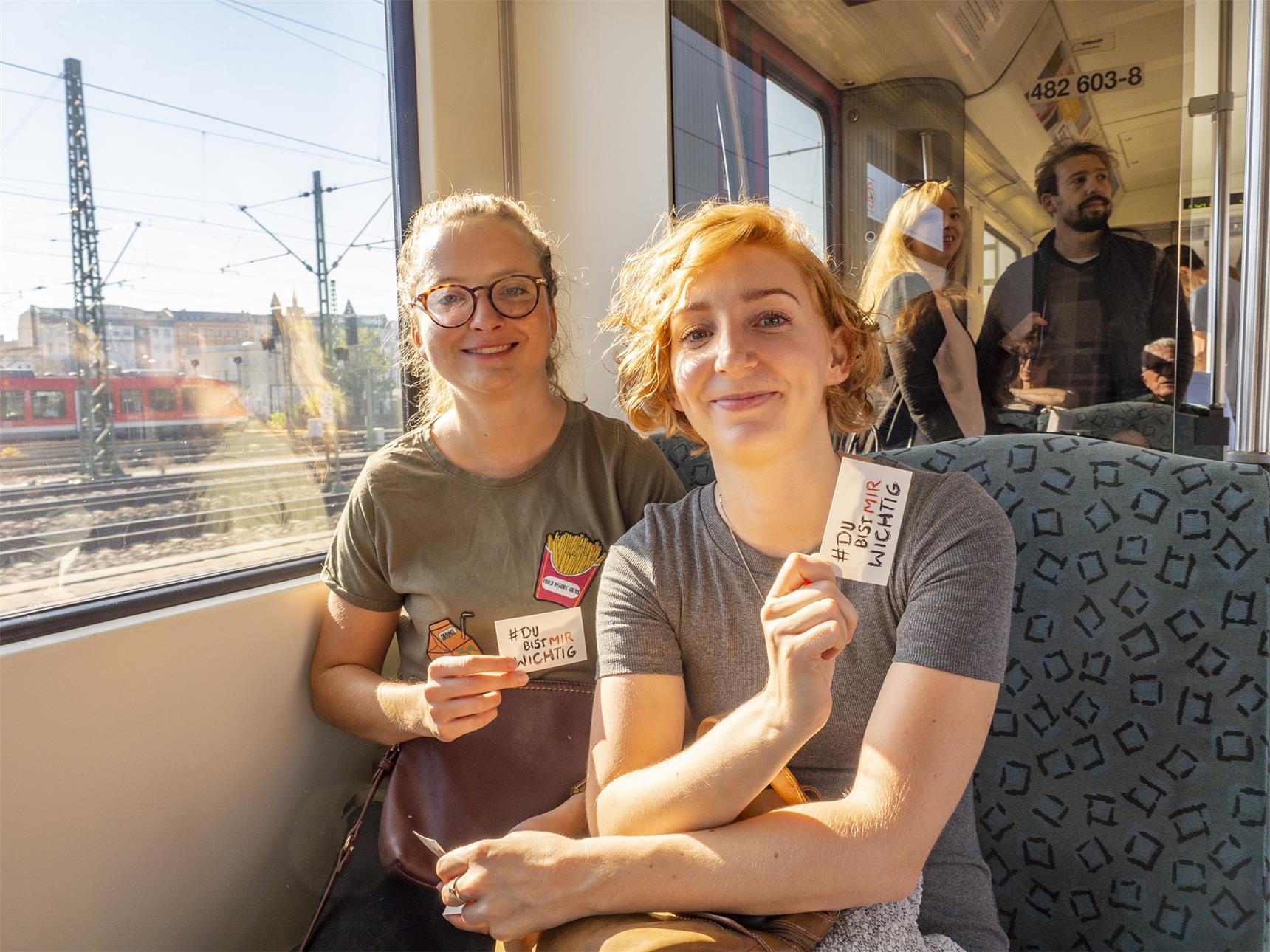 Zwei junge Frauen im Zug mit dem Aufkleber "Du bist mir wichtig" (Angela Kröll)