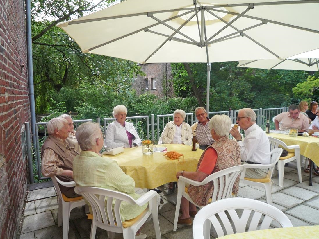 Senioren sitzen am Tisch auf der Terasse des Em Cavenn 