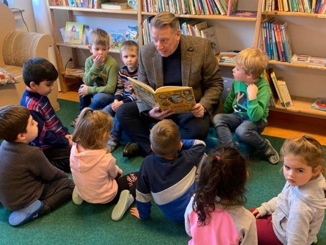 Ein Mann liest Kindern aus einem Buch vor. 