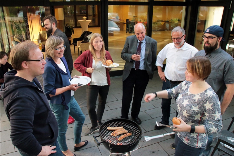 Das Foto zeigt eine Gruppe von Menschen rund um einen Grill.