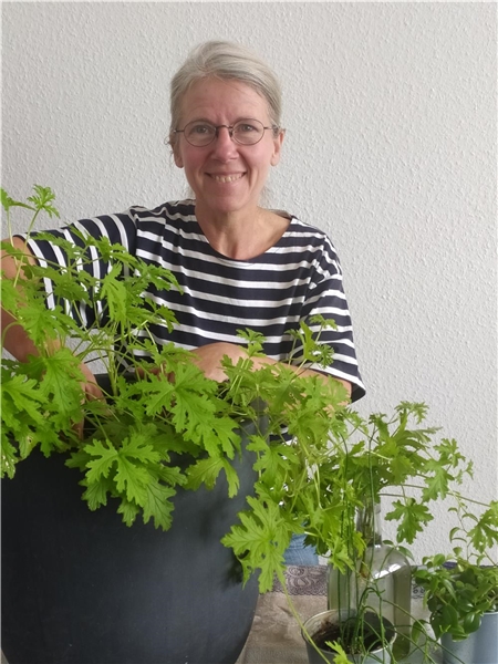 Annette Simmgen-Schmude steht hineter eine großblättrigen Grünpflanze.