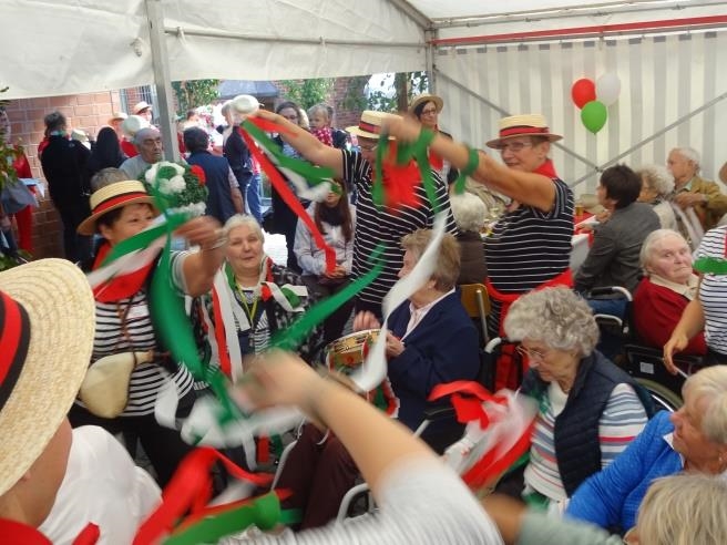Bewohner und Gäste schwingen Bänder in den italienischen Landesfarben (Seniorenzentrum St. Bonifatius)