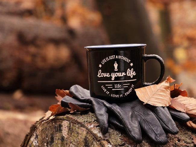 Tasse auf einem Holzstamm mit der Aufschrift "Love yourt Life"