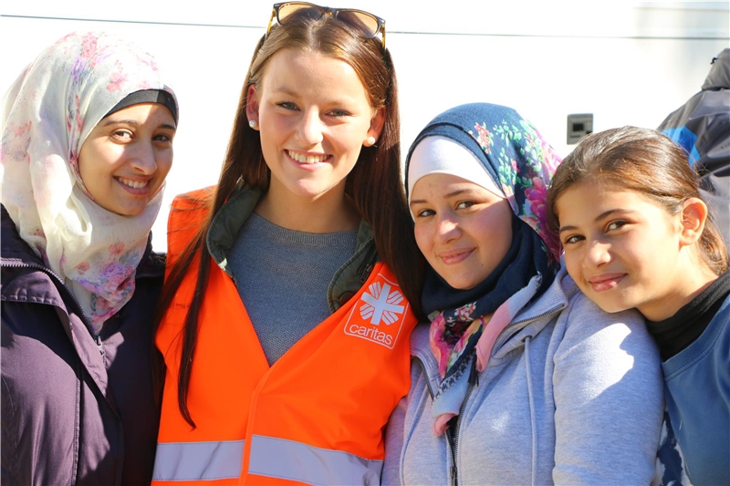 Das Foto zeigt eine kleine Gruppe von Menschen, eine deutsche Ehrenamtliche eingerahmt von jungen Flüchtlingen.