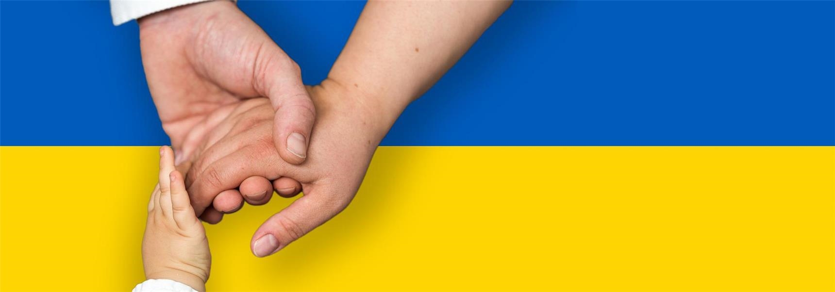 Hände symbolisieren Uusammenhalt vor ukrainischer Flagge