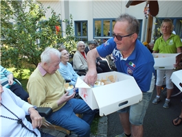 Ein Mann verteilt im Garten Eisbecher an die Bewohner / Foto: Schedlbauer
