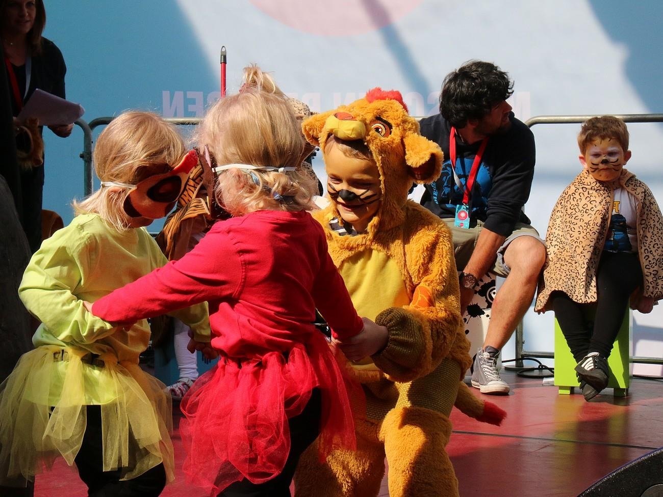 Drei Kinder im Kostüm tanzen im Kreis. 