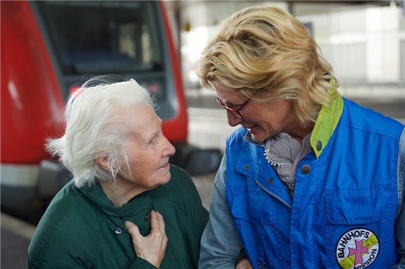 Mitarbeiterin der Bahnhofsmission unterhält sich mit älterer Frau