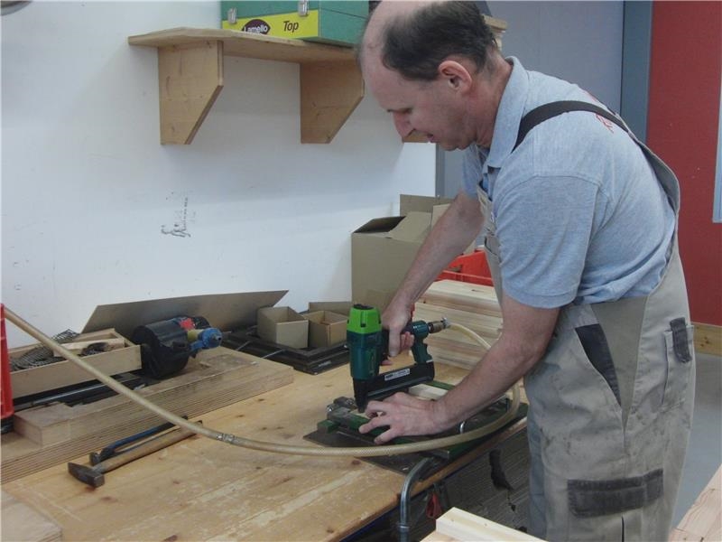 Ein Mitarbeiter fertigt Holzkisten mit dem Druckluftnagler. 