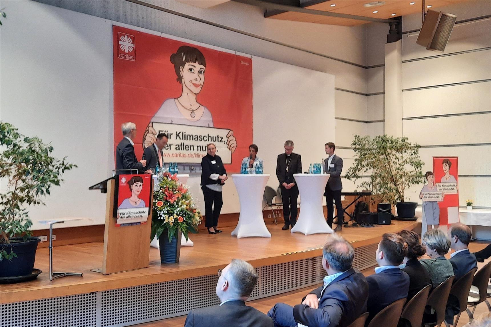 Blick auf ein Podium auf den an drei Stehtischen sechs Personen stehen  (Foto: Hessen Caritas)