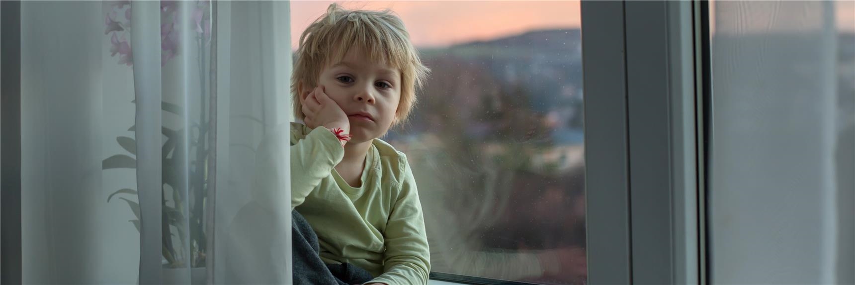 Ein Junge sitzt auf einer Fensterbank