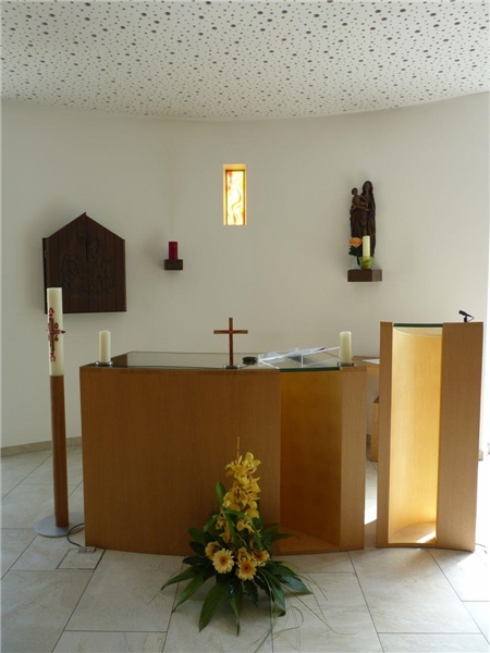 Wir blicken in eine helle Kapelle, deren Altar und Ambo aus Buchenholz und sakrale Teile aus Bronze bestehen.