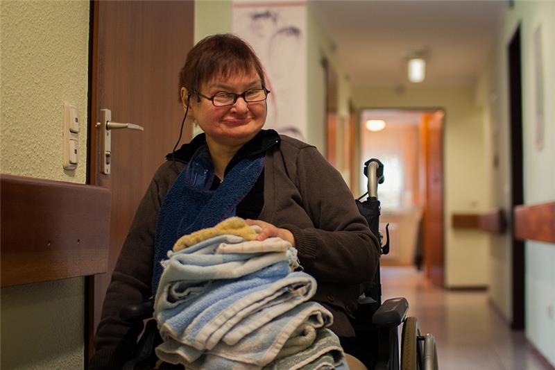 Bewohnerin im Rollstuhl mit Handtüchern auf ihrem Schoß 