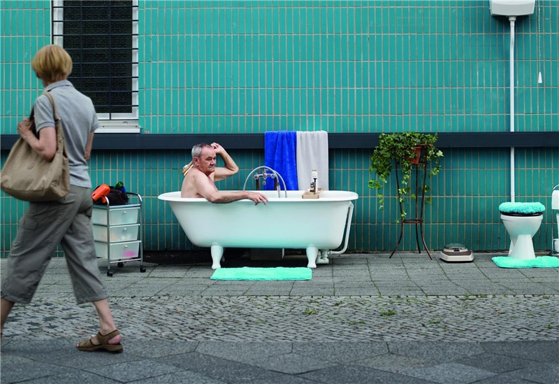 Ein älterer Mann sitzt in einer Badewanne in der Fußgängerzone