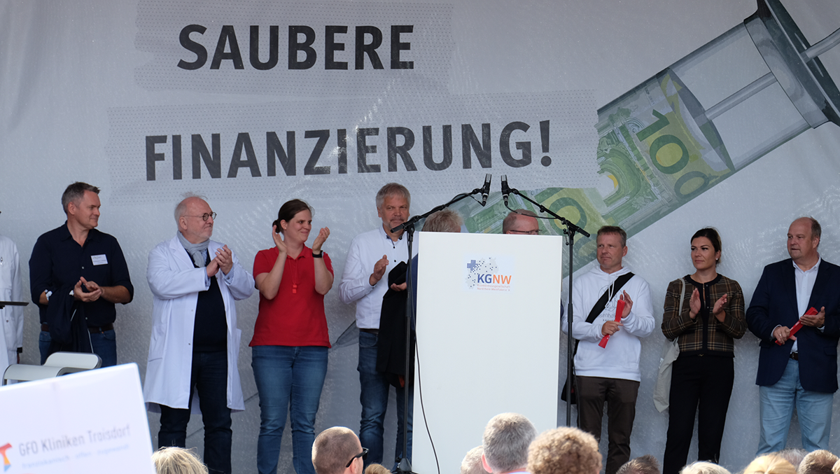 Die Bühne bei einer Kundgebung zur Krankenhausfinanzierung vor dem Düsseldorfer Landtag, auf der Vertreterinnen und Vertreter der Aktion stehen (Foto: Markus Lahrmann)