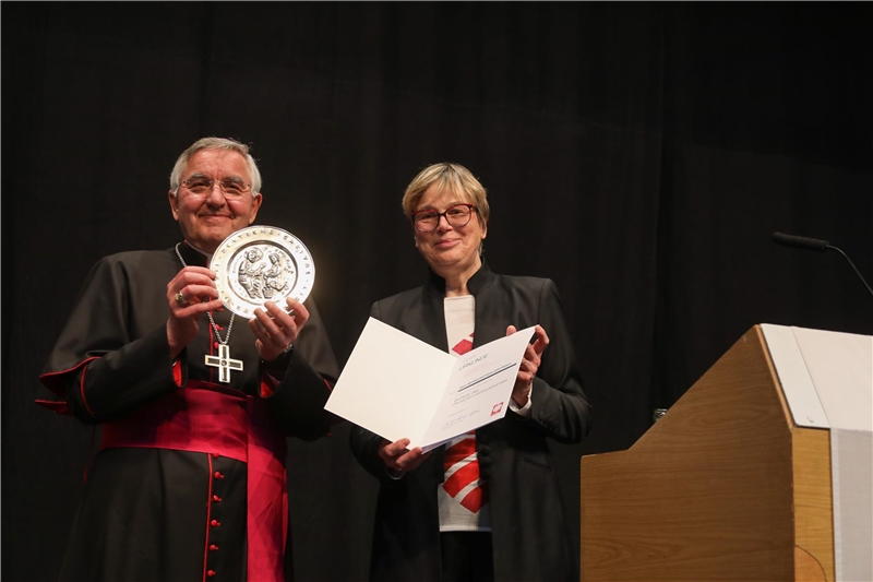 Weihbischof Franz Josef Gebert freut sich über den Brotteller, den ihm Caritas-Präsidentin Eva Maria Welskop-Deffaa überreicht hat.