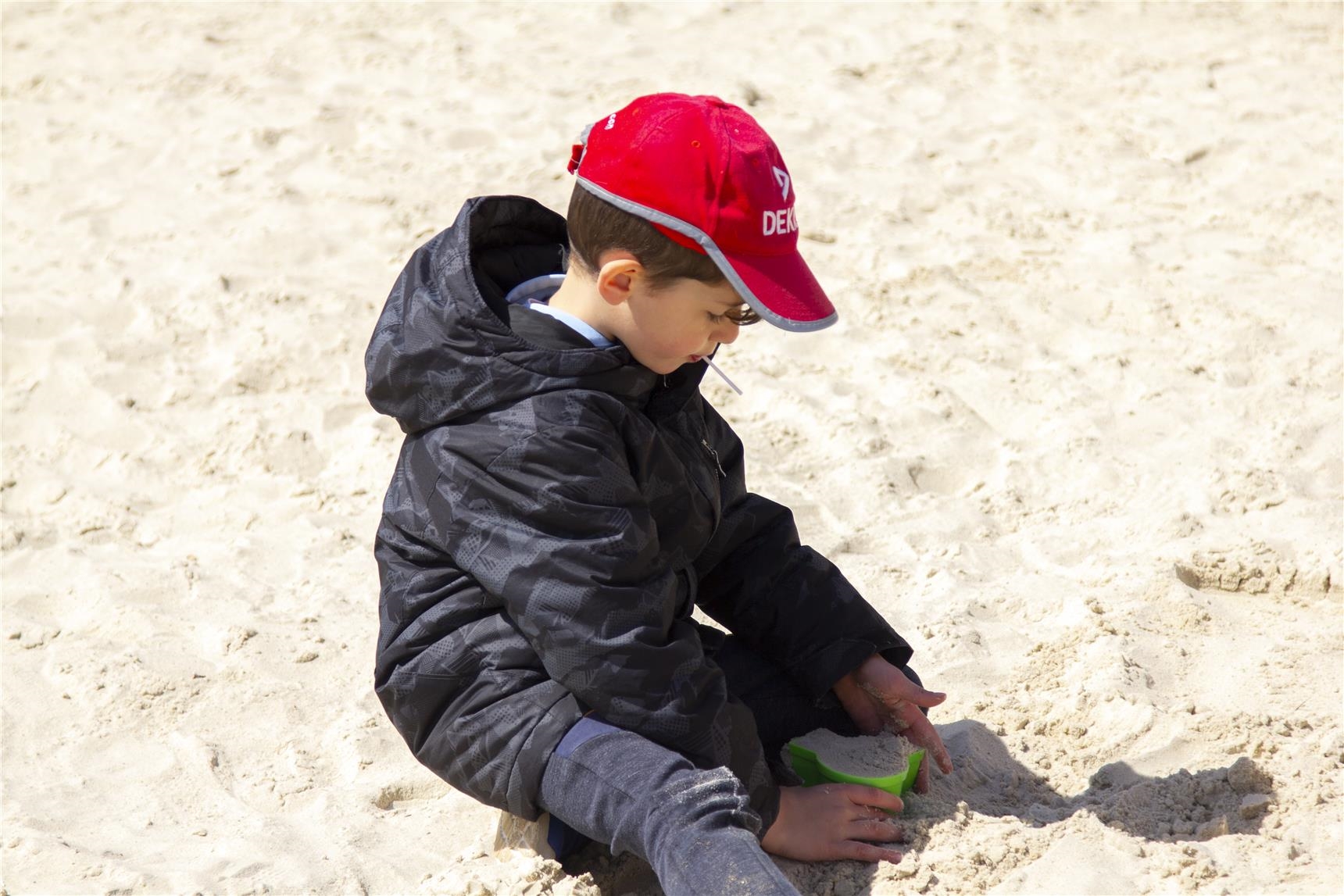 Ein Junge backt im Sandkasten einen Sandkuchen. 