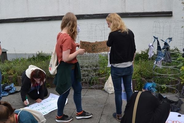 Fleißig schreiben die Jugendlichen die Schilder für den Drahtzaun (youngcaritas Deutschland)