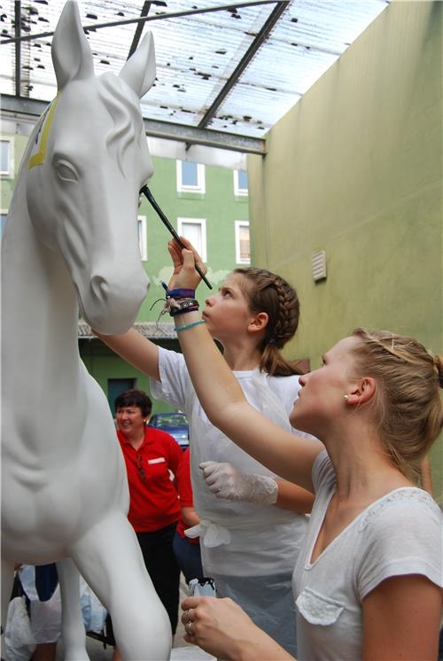 Zwei Mädchen malen Konturen der Motive auf den Pferdekopf (Caritas Speyer)