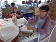 Zwei Bewohnerinnen beim Abwaschen an einem alten ausziehbaren Abwaschtisch mit Emailschüsseln. / Mario Horn
