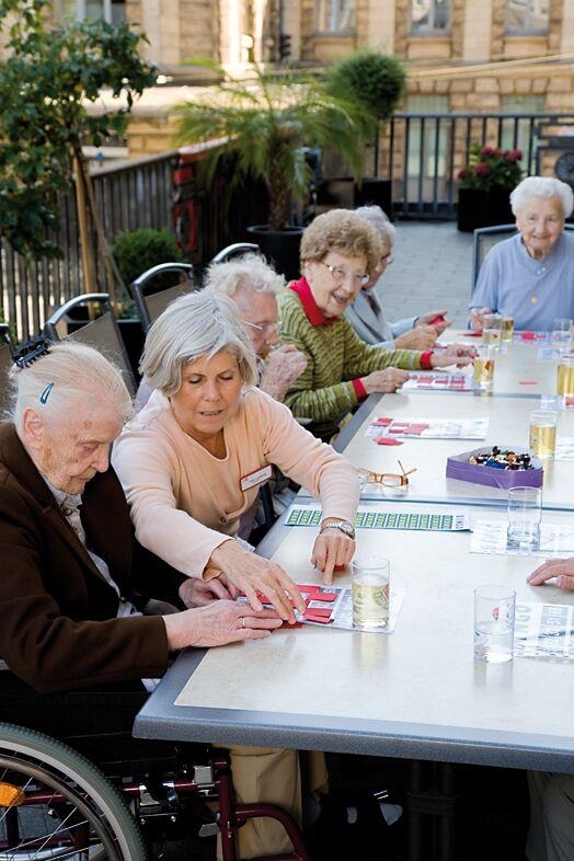Bewohner sitzen zusammen auf der Terrasse und spielen Bingo 