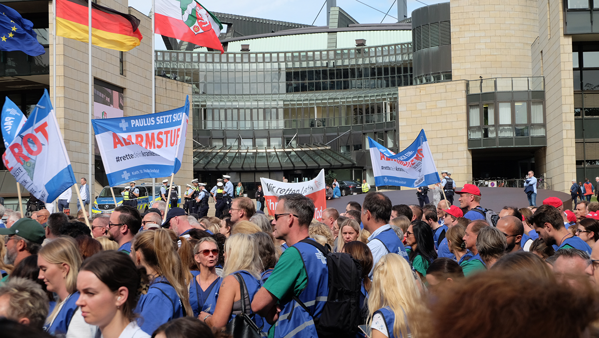 Demonstraten, die bei einer Kundgebung zur Krankenhausfinanzierung vor dem Düsseldorfer Landtag stehen und dabei Schilder und Transparente hochhalten (Foto: Markus Lahrmann)