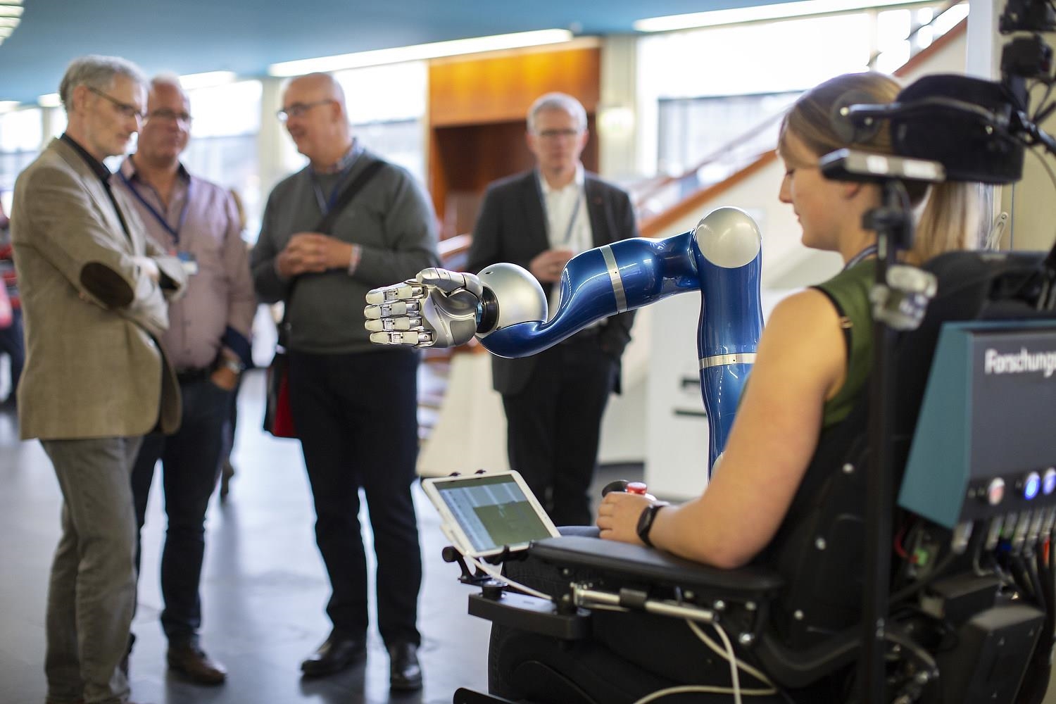 Frau testet vor Zuschauern einen Roboterarm auf dem Caritaskongress 2019 (DCV/Janine Schmitz)