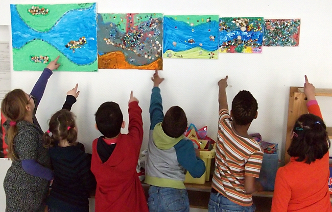 Kinder zeigen auf selbst gemalte Bilder (Caritasverband Remscheid)
