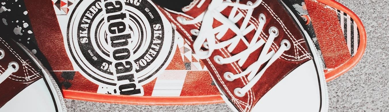 Ausschnitt von Schuhen auf einem Skateboard Header