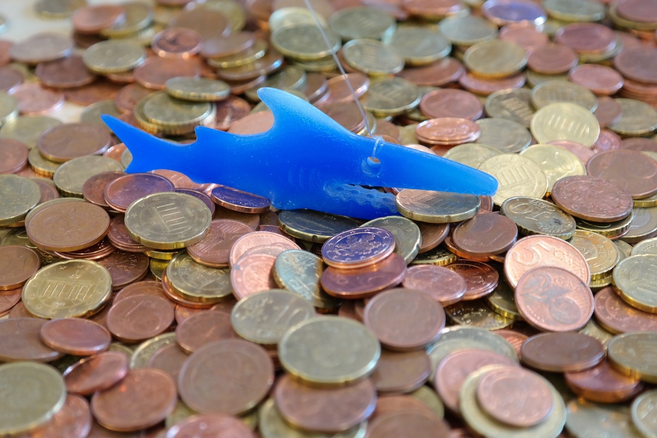 Haufen Kleingeld mit blauem Plastikhai