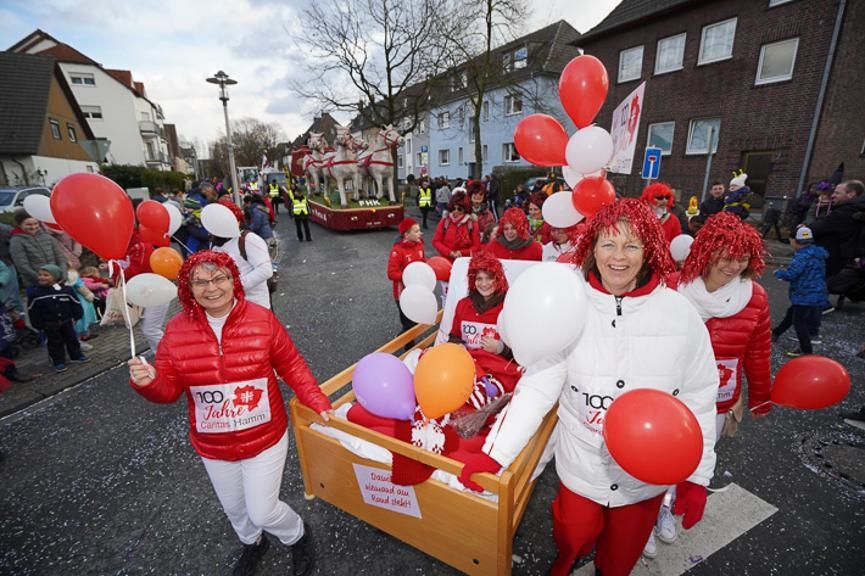Rot-weiß gekleidete Frauen mit roten Perücken und Luftballons schieben ein Pflegebett (WA Szkudlarek)