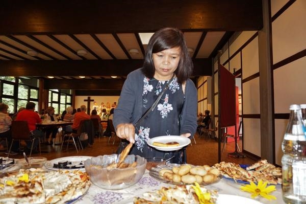Eine Besucherin mit asiatischem Migrationshintergrund am reich gedeckten Speisentisch. (Reinhard Biermann)